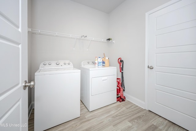 laundry room with baseboards, light wood-style flooring, laundry area, and washing machine and dryer