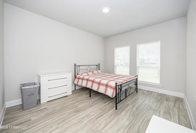 bedroom with light wood finished floors and baseboards