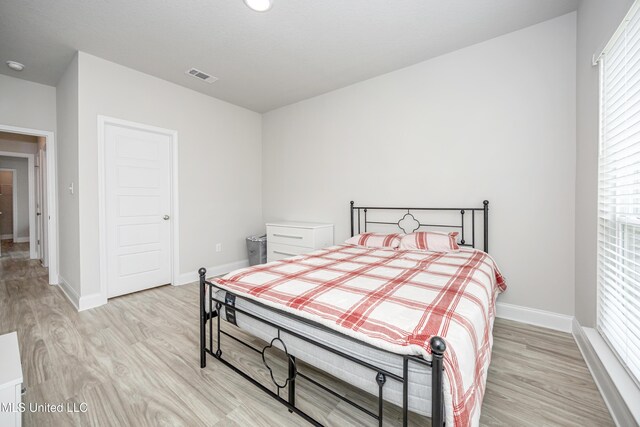 bedroom with light wood-style floors, visible vents, and baseboards