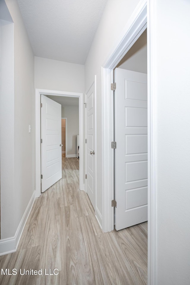 corridor with wood finished floors and baseboards