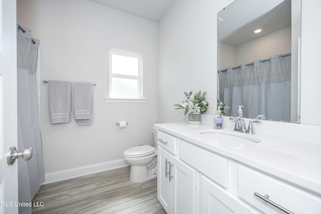 bathroom with wood finished floors, vanity, toilet, and baseboards