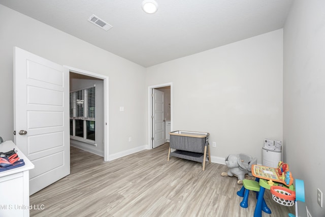 rec room with light wood-style floors, visible vents, and baseboards