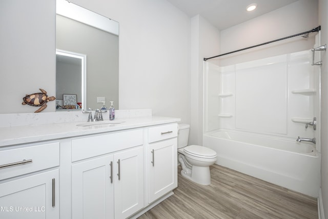 full bathroom with recessed lighting, wood finished floors, toilet, vanity, and washtub / shower combination