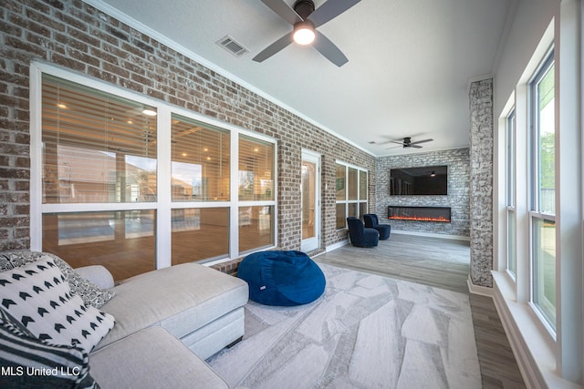 sunroom / solarium with a glass covered fireplace, ceiling fan, and visible vents