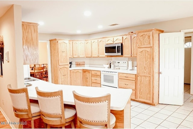 2208 Highland Dr, Gautier, MS 39553 - kitchen featuring stainless steel microwave, white electric range oven, light brown cabinets, a peninsula, and recessed lighting