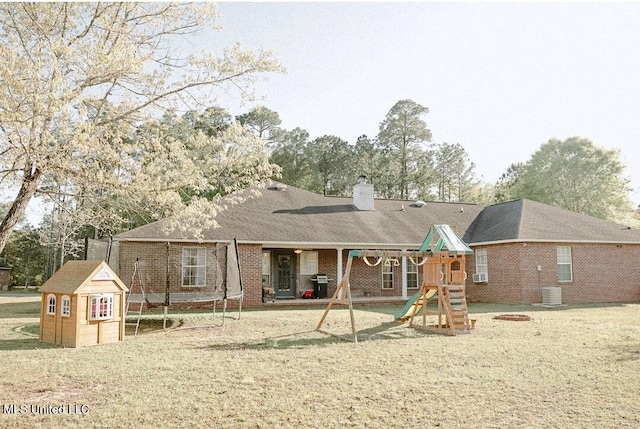 2208 Highland Dr, Gautier, MS 39553 - rear view of house featuring a playground, a trampoline, a chimney, brick siding, and a lawn