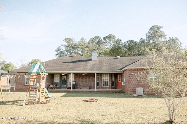 2208 Highland Dr, Gautier, MS 39553 - rear view of house with a playground, a trampoline, brick siding, a chimney, and a lawn