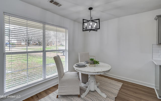 dining room with baseboards, wood finished floors, visible vents, and a notable chandelier