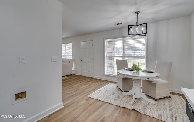 dining room featuring light wood-type flooring, baseboards, visible vents, and a chandelier