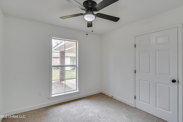 empty room featuring baseboards, a ceiling fan, and light colored carpet