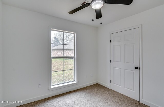 carpeted empty room with a ceiling fan and baseboards