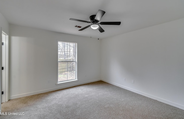 spare room featuring light carpet, ceiling fan, visible vents, and baseboards