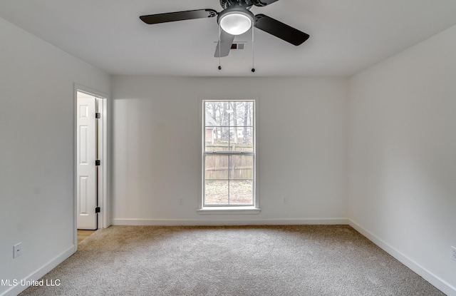 spare room with a ceiling fan, light colored carpet, visible vents, and baseboards