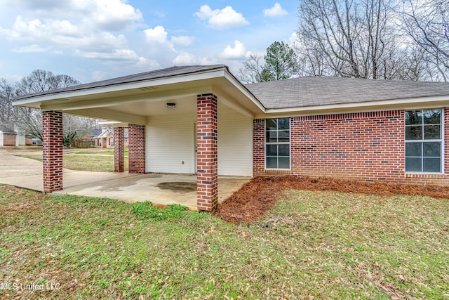 view of front of home featuring driveway, a front lawn, an attached carport, and brick siding