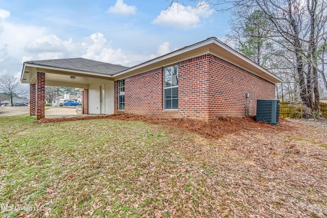 view of side of home featuring a yard, central AC, and brick siding