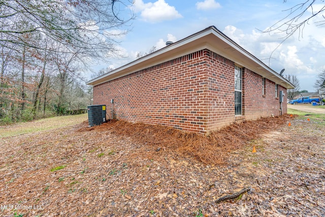 view of side of property with brick siding and central AC unit