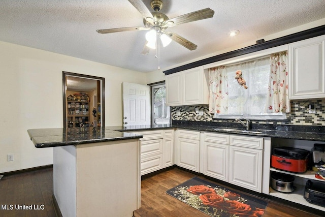 kitchen featuring white cabinets, dark hardwood / wood-style flooring, kitchen peninsula, and sink