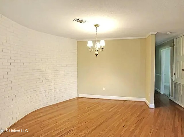 1704 Pat Dr, Gautier, MS 39553 - empty room with brick wall, visible vents, wood finished floors, baseboards, and an inviting chandelier