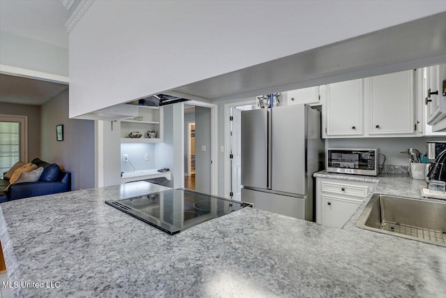 kitchen with open shelves, a sink, light stone counters, stainless steel appliances, and white cabinetry
