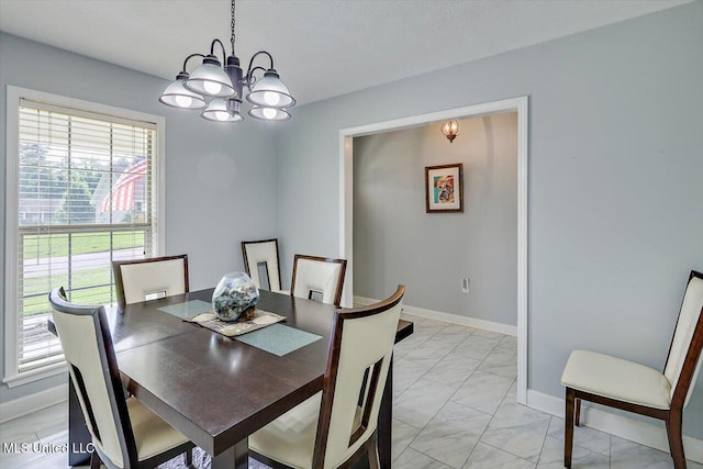 dining area with an inviting chandelier, marble finish floor, and baseboards