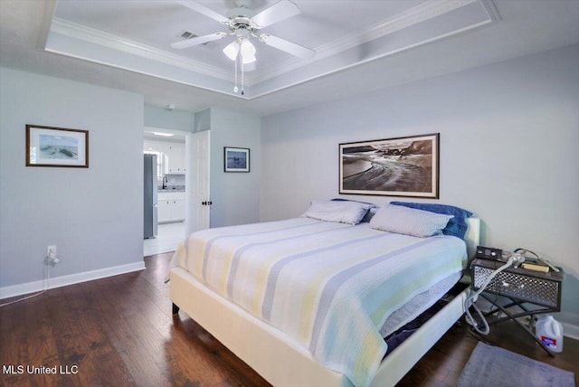 bedroom with baseboards, wood finished floors, a tray ceiling, visible vents, and ornamental molding