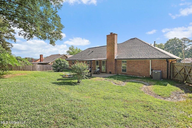 rear view of property featuring a fenced backyard, roof with shingles, a chimney, a patio area, and a lawn