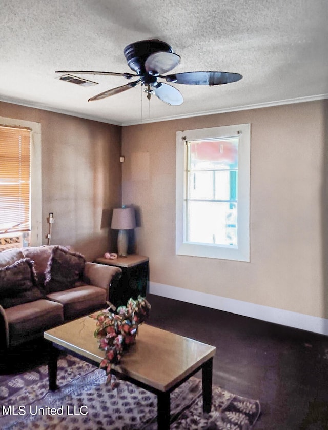 living room with ceiling fan, a textured ceiling, and ornamental molding