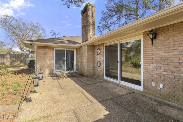 back of house with fence, brick siding, a chimney, and a patio area