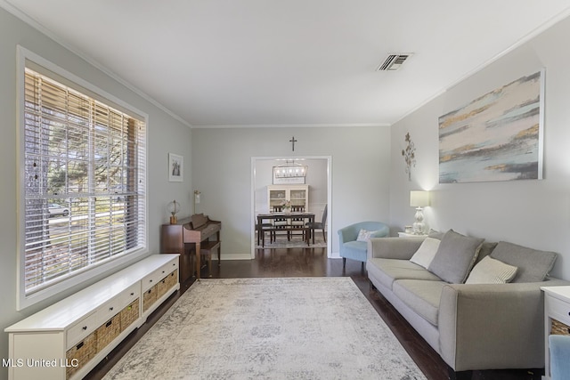 living room with baseboards, visible vents, dark wood finished floors, crown molding, and a chandelier