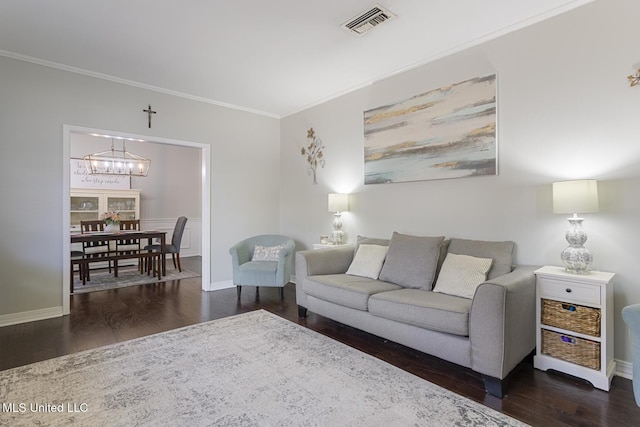 living room with visible vents, ornamental molding, an inviting chandelier, and wood finished floors