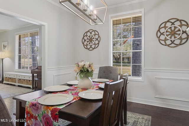 dining space featuring crown molding, a decorative wall, dark wood-style floors, and wainscoting