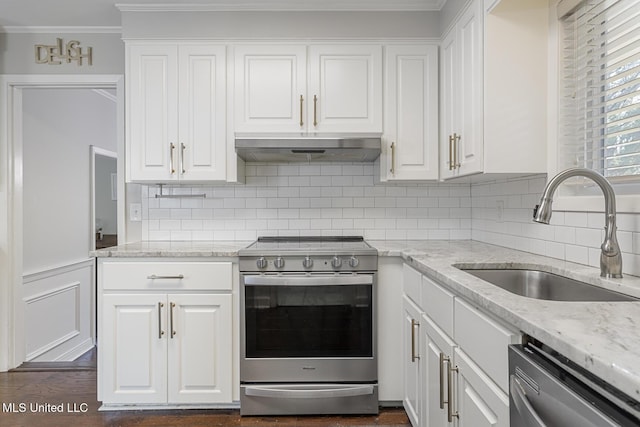 kitchen with under cabinet range hood, a sink, appliances with stainless steel finishes, white cabinets, and crown molding