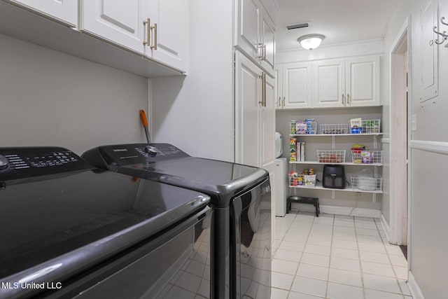 washroom with visible vents, cabinet space, light tile patterned floors, baseboards, and washing machine and clothes dryer