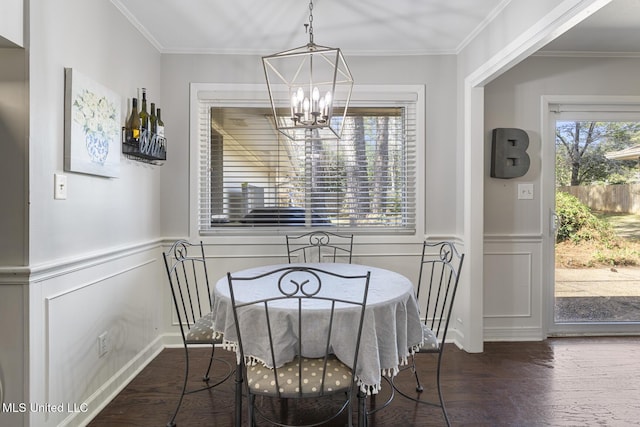 dining room with an inviting chandelier, wood finished floors, wainscoting, and crown molding