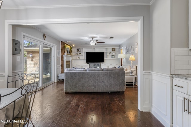 living room featuring ceiling fan, dark wood finished floors, ornamental molding, and wainscoting