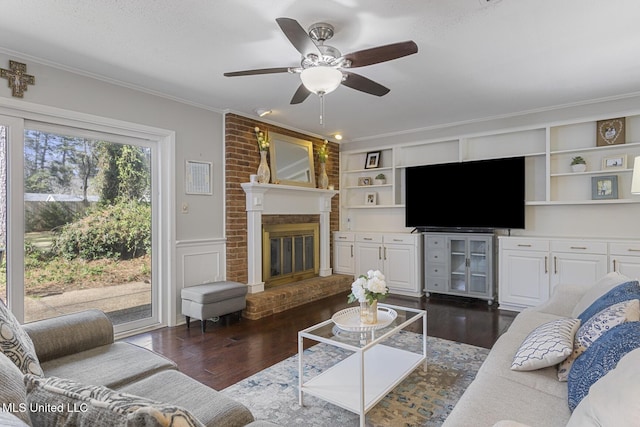 living room with a wainscoted wall, dark wood-type flooring, a fireplace, and crown molding