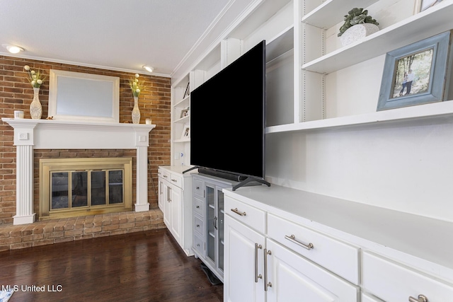 unfurnished living room with crown molding, brick wall, dark wood-type flooring, and a fireplace