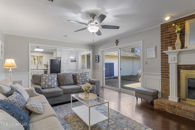 living area featuring ornamental molding, wainscoting, a fireplace, and hardwood / wood-style flooring