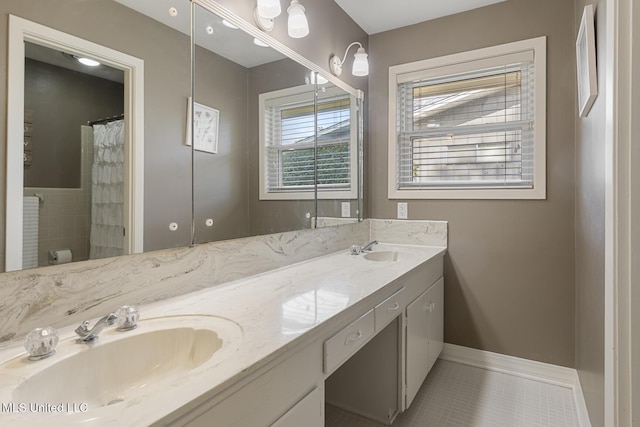 full bathroom featuring a sink, baseboards, double vanity, and tile patterned floors