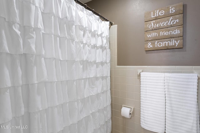 bathroom with curtained shower and tile walls