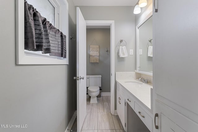 bathroom featuring vanity, toilet, and baseboards