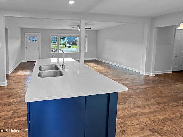 kitchen featuring sink, ceiling fan, an island with sink, blue cabinets, and dark hardwood / wood-style flooring