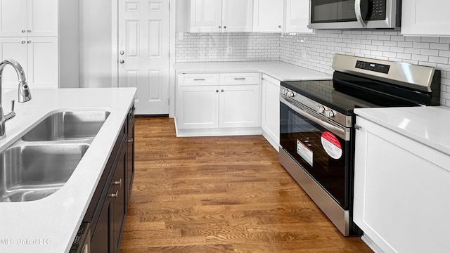 1049 Idlewild St, Memphis, TN 38107 - kitchen featuring stainless steel appliances, a sink, wood finished floors, and white cabinetry