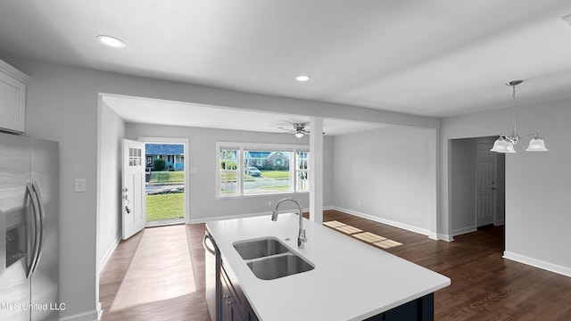 kitchen featuring sink, appliances with stainless steel finishes, dark hardwood / wood-style floors, hanging light fixtures, and a kitchen island with sink