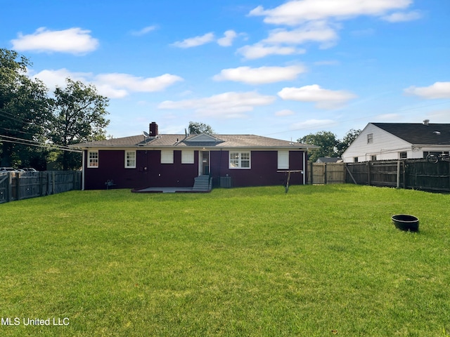 rear view of house with central AC and a yard