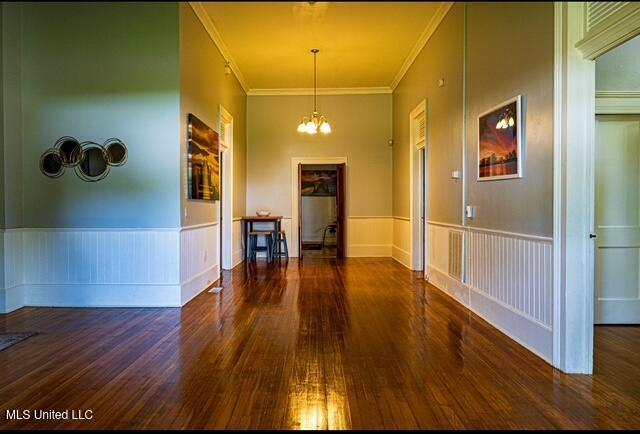 733 S College St, Grenada, MS 38901 - hallway featuring wood-type flooring, a chandelier, crown molding, and wainscoting