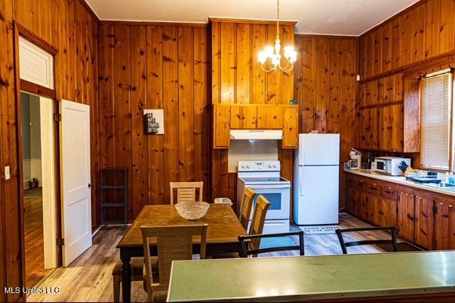 733 S College St, Grenada, MS 38901 - kitchen with white appliances, under cabinet range hood, a chandelier, light wood-style flooring, and wooden walls