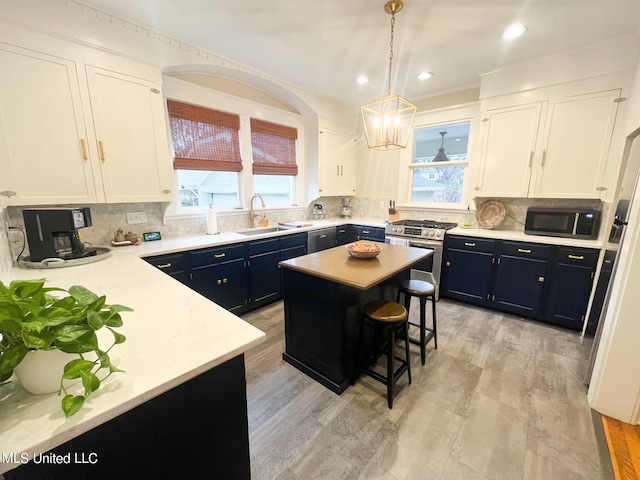 kitchen with a wealth of natural light, a center island, white cabinets, and appliances with stainless steel finishes