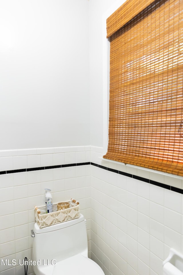 bathroom featuring toilet and tile walls