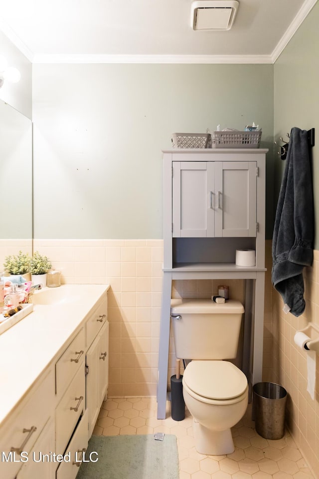 bathroom with tile patterned flooring, toilet, tile walls, and ornamental molding